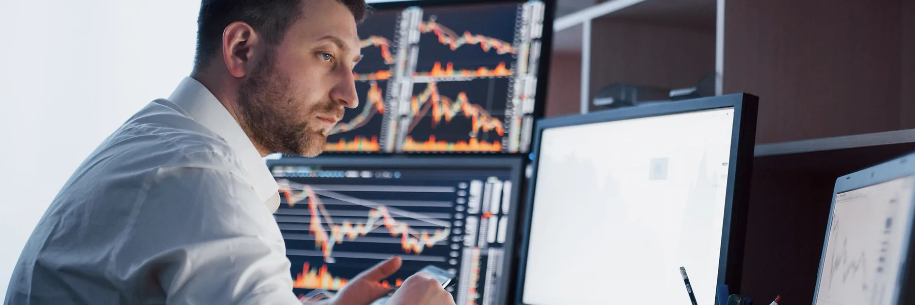 Trader at a desk watching price charts across several monitors